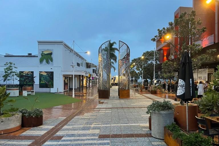 The Strand in central Tauranga, paved city street lined with hospitality frontages and palms