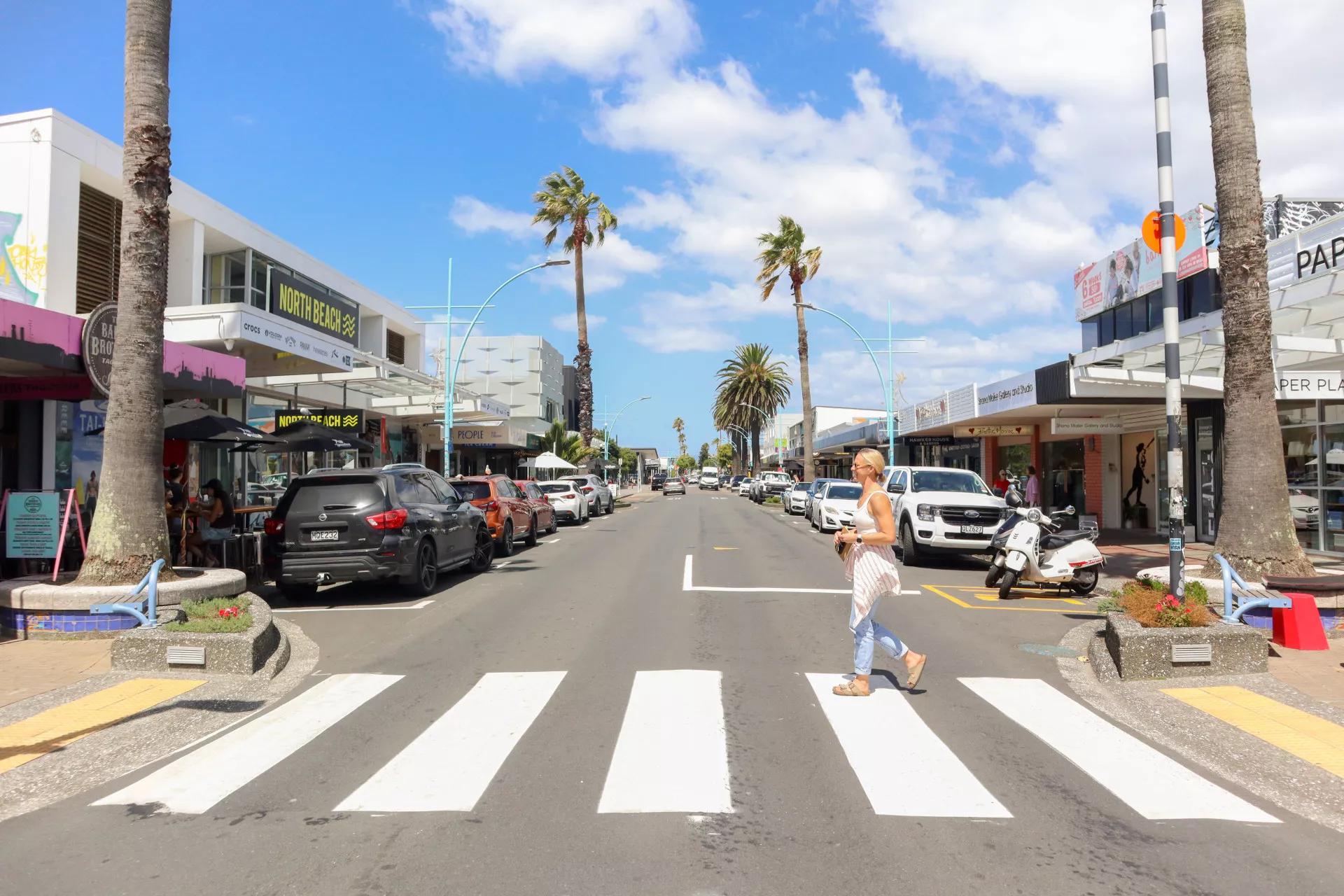 Maunganui Road looking down the main street, shopfronts either side and a pedestrian crossing in the foreground