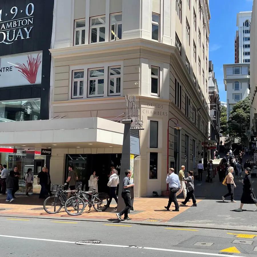 A crowded city footpath at lunchtime, shopfronts along one side